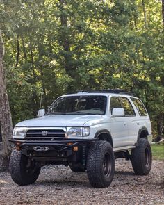 a white truck parked in the woods next to trees