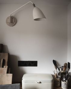 a kitchen counter with utensils on it and a wall light hanging from the ceiling