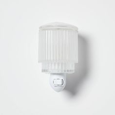 a white wall mounted light with a plastic covering on it's side and an electrical outlet in the middle