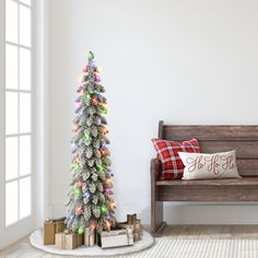 a small christmas tree next to a bench with presents on the floor and a pillow