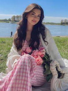 a woman sitting on the grass with flowers in her lap