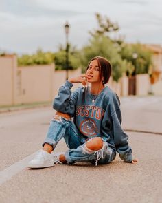 a woman sitting on the ground with her hand under her chin