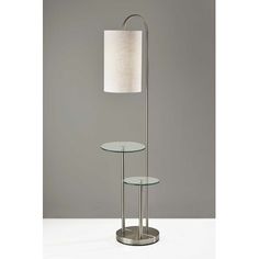 a lamp that is on top of a glass table next to a light fixture with a white shade