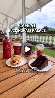 two plates with food on them sitting on a wooden table under an awning that reads cafe at buckingham palace