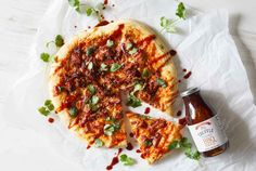 a pizza on a piece of paper next to a bottle of beer