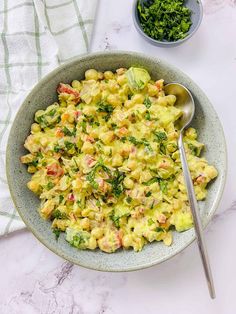 a bowl filled with macaroni salad next to a spoon