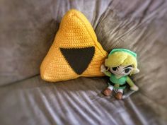 a crocheted zelda doll next to a stuffed animal on a couch with a pillow