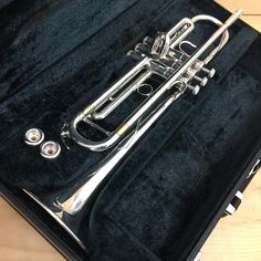 a silver trumpet in a black case on a wooden table