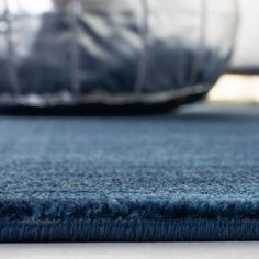 a close up view of a blue carpet with a pillow on the floor in the background