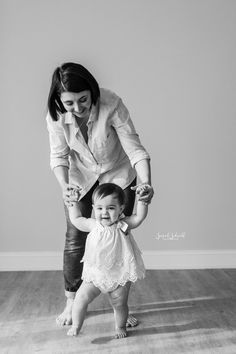 a woman holding the hand of a small child in front of her face while standing on top of a hard wood floor