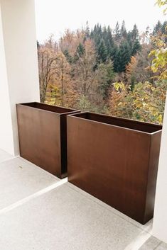 two large metal planters sitting on top of a white floor next to a window