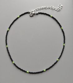 A minimalist black handmade necklace with green coloured bead details Green Beaded Necklace With Black Round Beads, Green Jewelry With Black Beads As A Gift, Green Jewelry With Black Beads For Gift, Minimalist Beads For Jewelry Making, Minimalist Green Necklaces For Jewelry Making, Trendy Green Necklaces With Tiny Beads, Trendy Black Necklace With Colorful Beads, Handmade Minimalist Green Beaded Necklace, Handmade Minimalist Beads