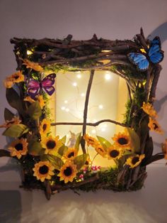 a lighted window with sunflowers and butterflies on the outside, in front of a white wall