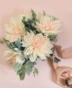 a bouquet of flowers sitting on top of a pink surface next to a beige scarf