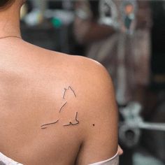 the back of a woman's shoulder with a small horse tattoo on her left shoulder