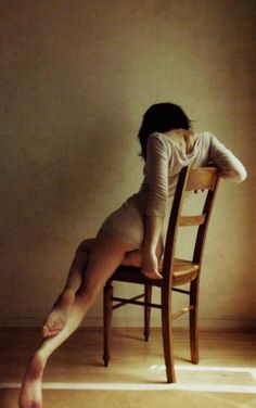 a woman sitting on top of a wooden chair