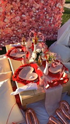 the table is set with plates, silverware and red napkins for valentine's day