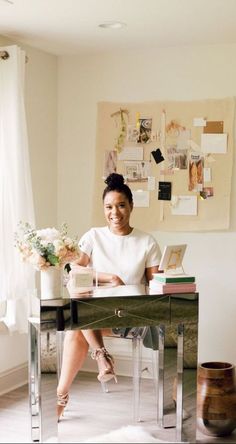 a woman sitting at a desk with flowers in front of her