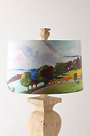 a table lamp with a painting on it sitting on top of a wooden stand next to a white wall