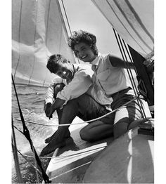 two men sitting on the front of a sailboat