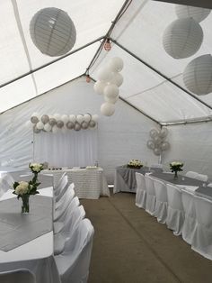 tables and chairs are set up in a tent with white linens on the floor