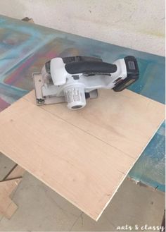 a sanding machine sitting on top of a piece of plywood