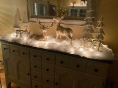 christmas decorations on top of a dresser in a room with a mirror and window behind it