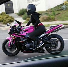 a woman riding on the back of a pink motorcycle