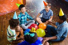 children sitting on the floor surrounded by balloons and confetti