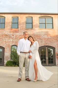 a man and woman standing in front of a brick building