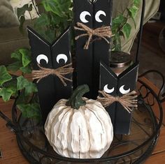 three black and white pumpkins with eyes painted on them sitting on a metal stand