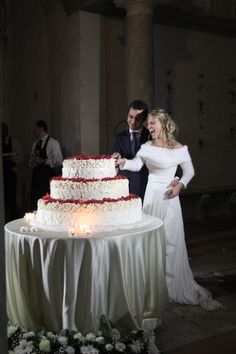 a bride and groom are cutting their wedding cake at the reception table with candles in front of them