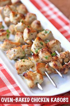 chicken kabobs on a white plate with red and white checkered table cloth