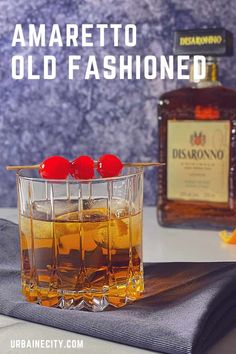 an old fashioned whiskey with cherries on the rocks in front of it and a bottle of disarrono