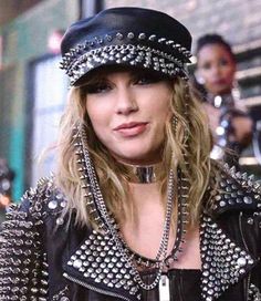 a woman with lots of spikes on her head wearing a black leather jacket and hat