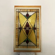 a stained glass window mounted to the side of a white wall with a wooden frame