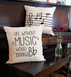 two pillows sitting on top of a table next to a vase with flowers in it