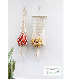 two macrame bags hanging on the wall next to a potted plant and cacti