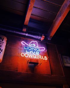 a neon sign that says long live cowgirls on the side of a building