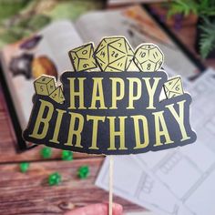 a hand holding up a happy birthday sign with dices on it and green candies around the edges