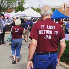 people walking down the street at an outdoor flea market with tents and umbrellas in the background