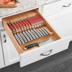 an open drawer in a kitchen filled with knives and utensils on top of a counter