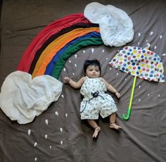 a small child laying on top of a bed next to an umbrella and other items