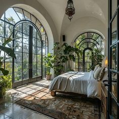 a bedroom with large arched windows and a bed in the middle, surrounded by greenery