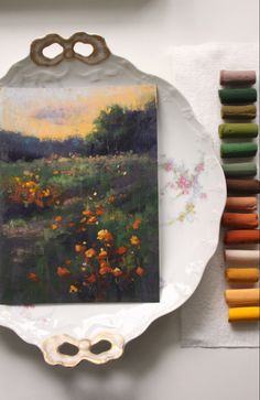 a painting on a plate next to some crayons