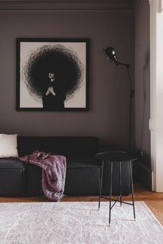 a living room with a black couch, white rug and a painting on the wall