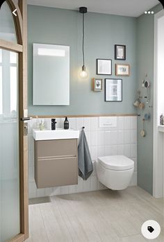 a white toilet sitting next to a sink in a bathroom under framed pictures on the wall