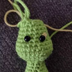 a crocheted green object with black eyes on it's head and neck