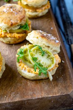 small sandwiches with pickles and cheese are on a wooden cutting board, ready to be eaten