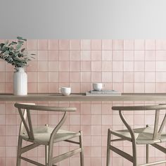 two chairs and a table in front of a pink tiled wall